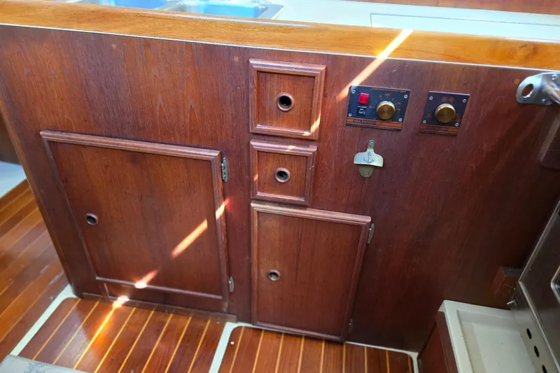 Slide: The Image of Wooden interior of a 1990 Pearson 385 sailboat, featuring cabinets and control panels. - 17