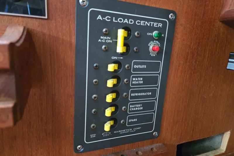 Slide: The Image of A-C load center panel on 1990 Pearson 385 boat, featuring switches and indicators. - 14