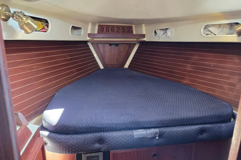 Slide: The Image of Cozy cabin interior of a 1990 Pearson 385 sailboat with wooden paneling and cushioned berth. - 19