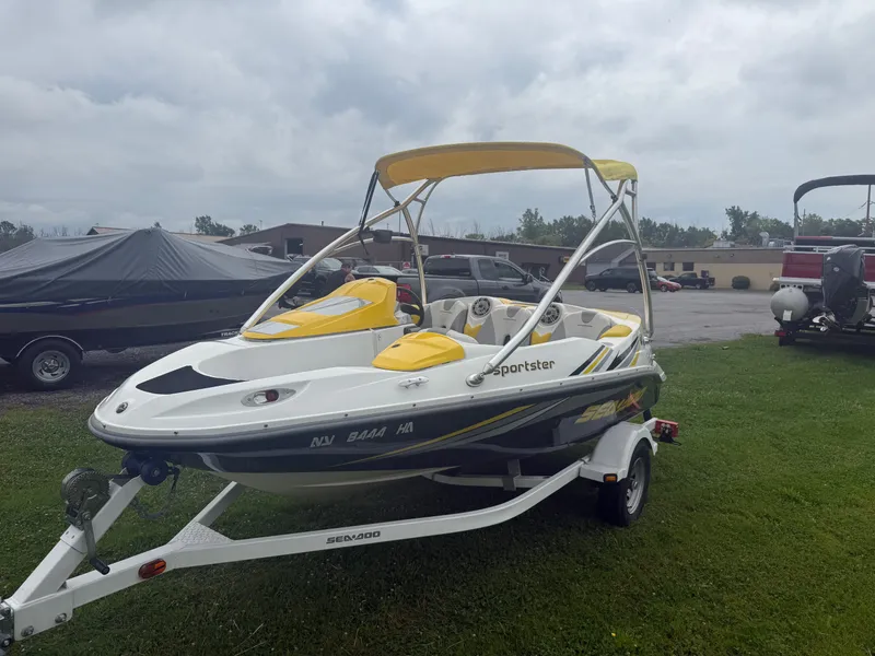 Slide: The Image of A 2006 Sea-Doo Sportster SCIC with yellow and white design sits on a trailer on grass. - 3