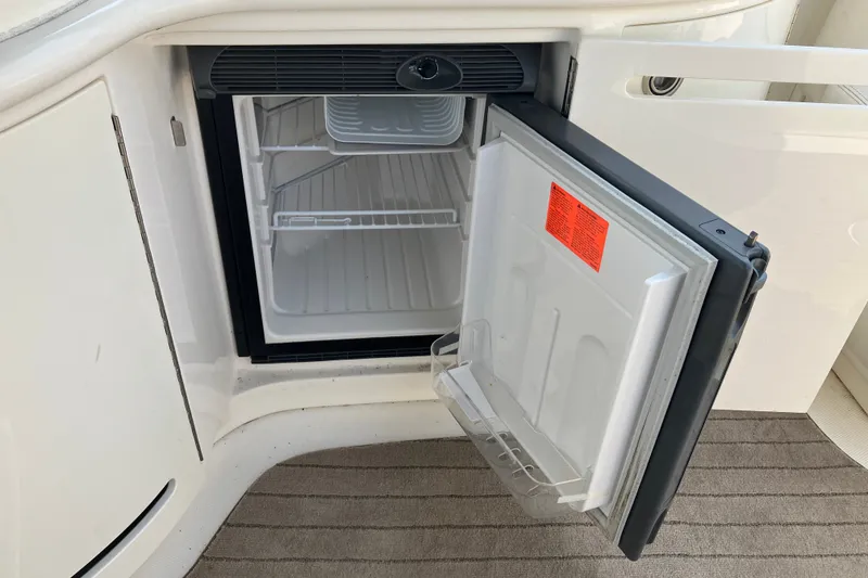 Slide: The Image of Open mini fridge on 2006 Sea Ray 290 Sun Sport boat, showing interior shelves. - 18
