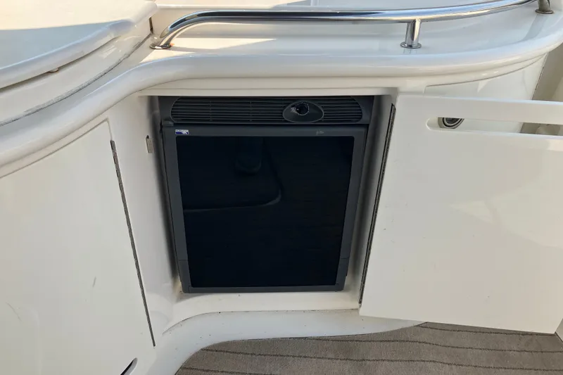 Slide: The Image of 2006 Sea Ray 290 Sun Sport boat interior with mini fridge and open cabinet door. - 17