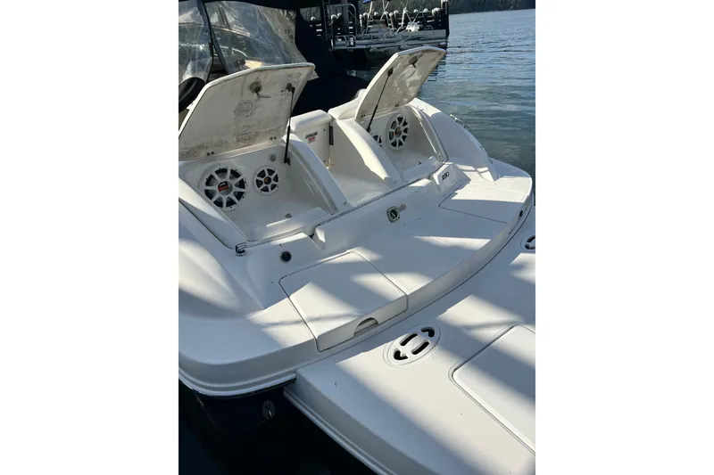 Slide: The Image of 2006 Sea Ray 290 Sun Sport boat with open storage compartments, docked on calm water. - 30
