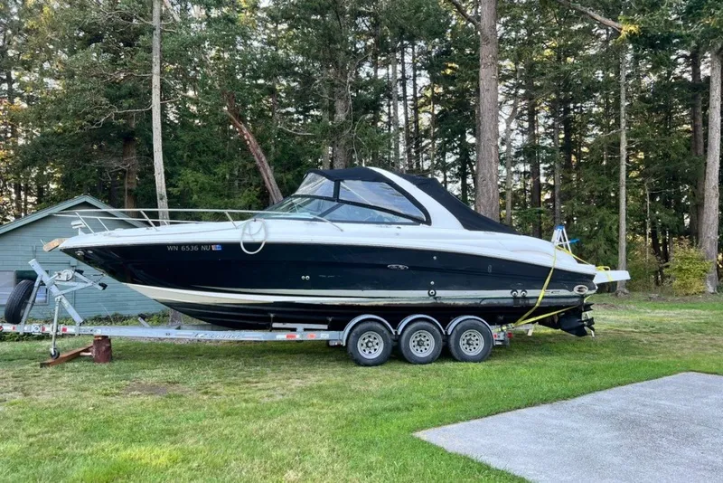 Slide: The Image of 2006 Sea Ray 290 Sun Sport boat on trailer, parked on grass near trees. - 29