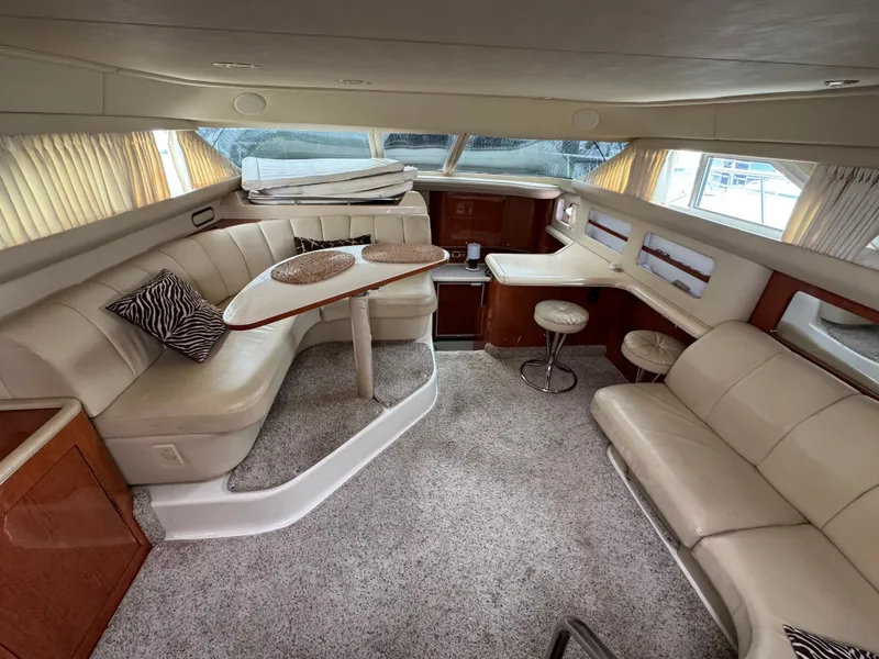 Slide: The Image of Interior of a 2000 Sea Ray 420 Aft Cabin with beige sofa and dining table. - 6