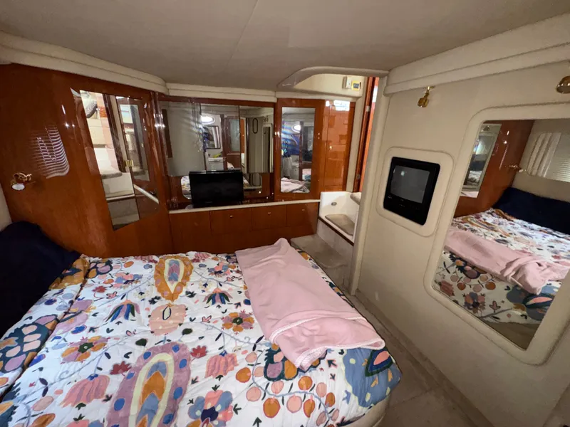 Slide: The Image of The cabin of a 2000 Sea Ray 420 Aft Cabin with a cozy bed and a TV. - 14