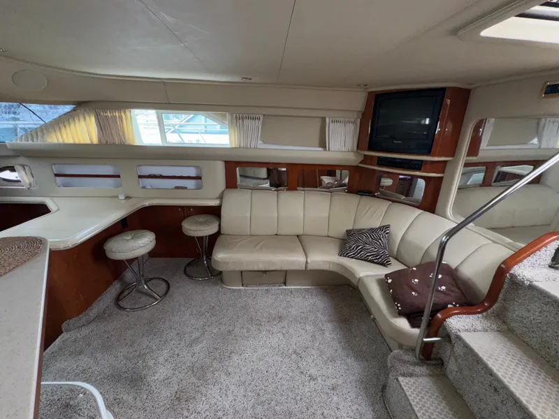 Slide: The Image of Interior of the 2000 Sea Ray 420 Aft Cabin with beige sofa, carpeted floor, and TV. - 8