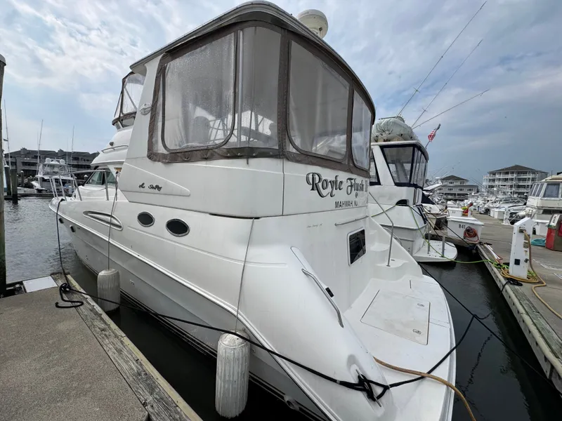 Slide: The Image of A 2000 Sea Ray 420 Aft Cabin docked at a marina. It features a spacious aft deck. - 2