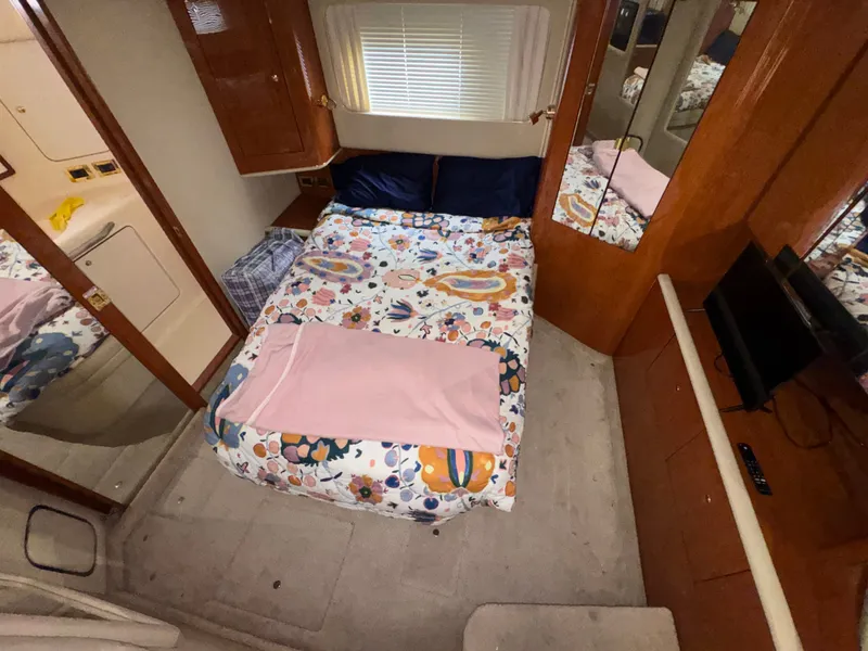 Slide: The Image of The cabin of a 2000 Sea Ray 420 Aft Cabin with a cozy bed and a TV. - 11