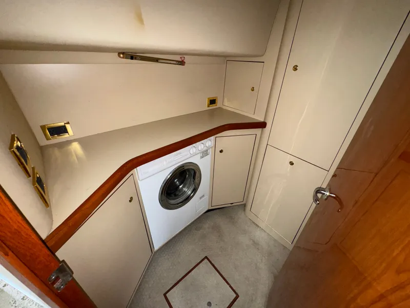 Slide: The Image of The laundry area of the 2000 Sea Ray 420 Aft Cabin features a washing machine and storage. - 16