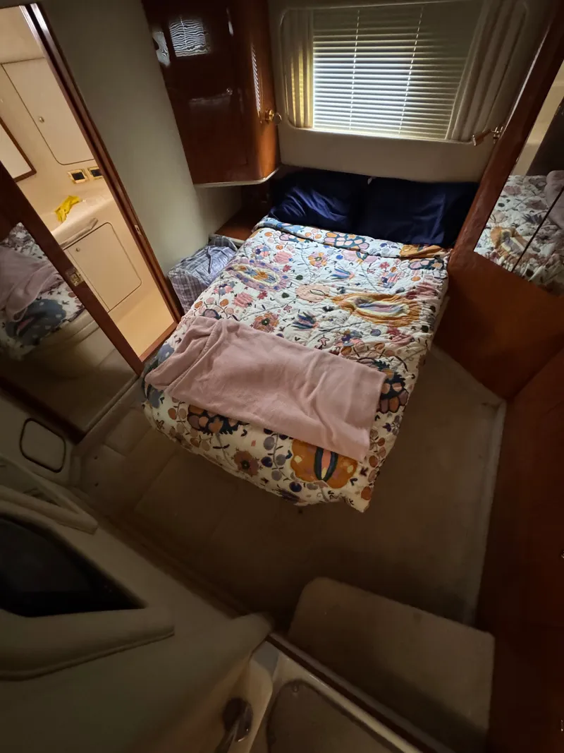 Slide: The Image of The cabin of a 2000 Sea Ray 420 Aft Cabin with a cozy bed and wooden furnishings. - 10