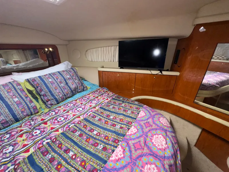 Slide: The Image of The cabin of a 2000 Sea Ray 420 Aft Cabin with a colorful bed and a TV. - 19