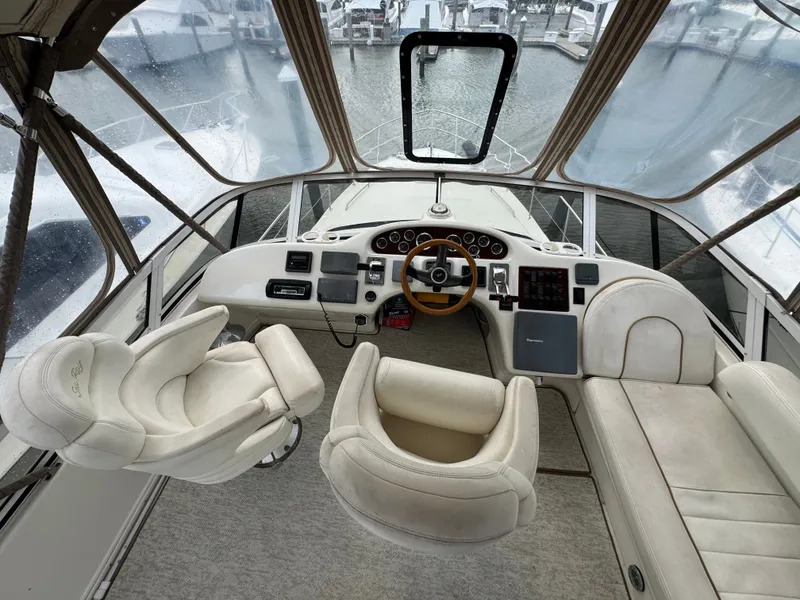 Slide: The Image of The image shows the cockpit of a 2000 Sea Ray 420 Aft Cabin with white leather seats and a wooden steering wheel. - 3