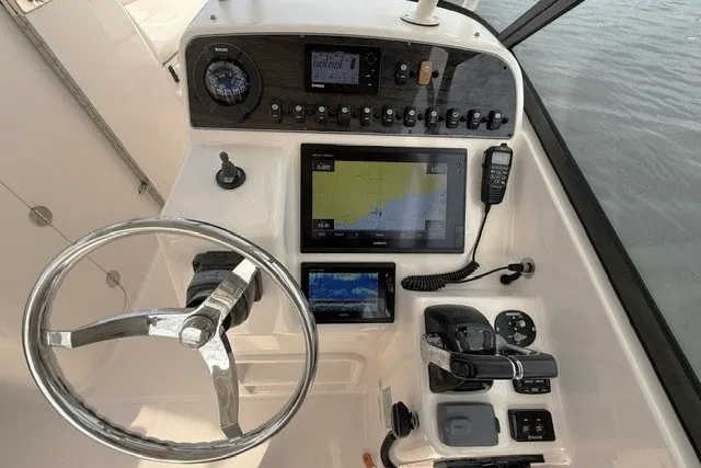 Slide: The Image of 2015 Grady-White Freedom 285 boat dashboard with steering wheel and navigation controls. - 9