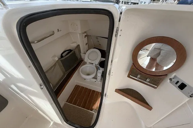 Slide: The Image of 2015 Grady-White Freedom 285 boat interior with compact bathroom and wooden accents. - 14