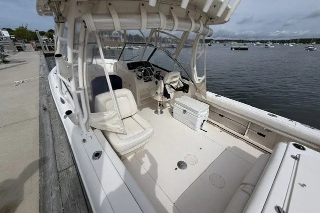 Slide: The Image of 2015 Grady-White Freedom 285 boat docked by the waterfront, showcasing spacious seating and helm. - 6