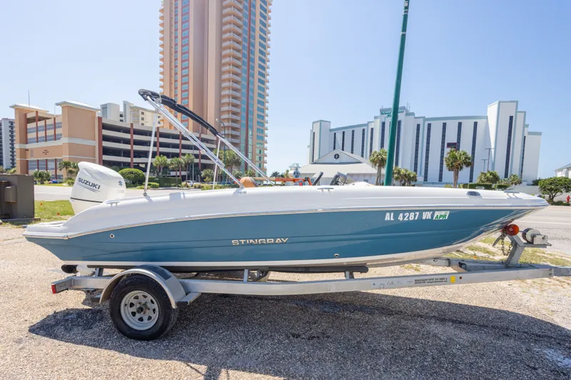 Slide: The Image of 2021 Stingray 182 SC boat on trailer, parked near tall buildings, sunny day. - 9