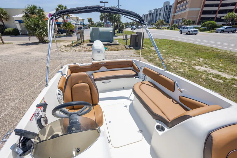 Slide: The Image of 2021 Stingray 182 SC boat with tan seating, parked near a road and buildings. - 30