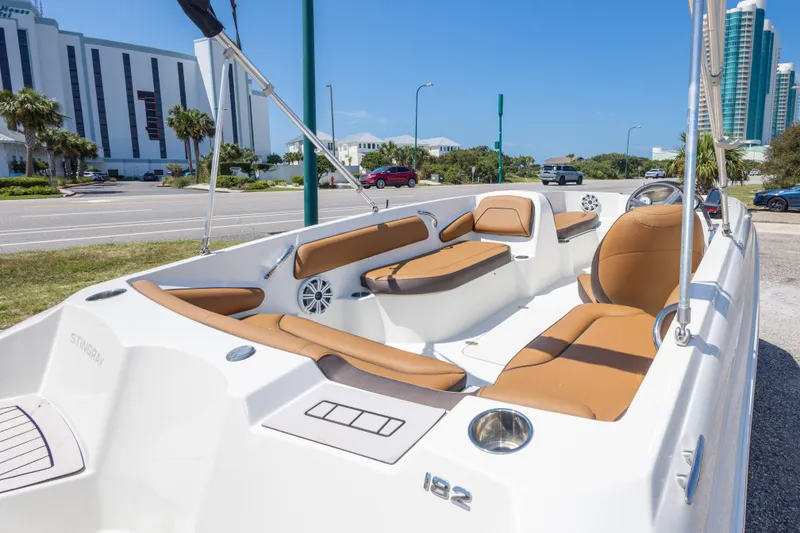 Slide: The Image of 2021 Stingray 182 SC boat with tan seating, parked near modern buildings. - 19
