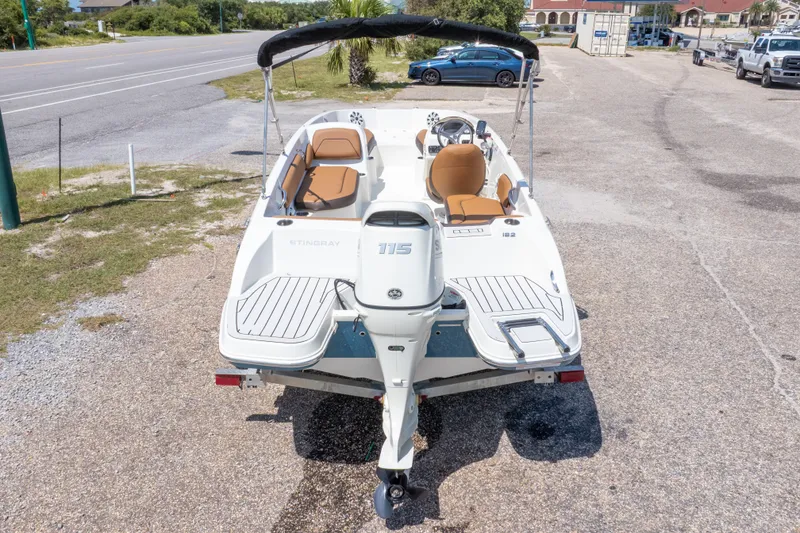 Slide: The Image of 2021 Stingray 182 SC boat with tan seats, parked on a trailer near a road. - 39