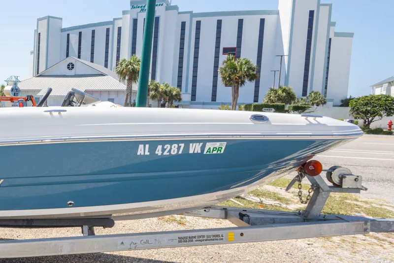Slide: The Image of 2021 Stingray 182 SC boat on trailer, parked near a modern building. - 11