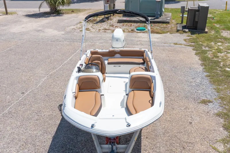 Slide: The Image of 2021 Stingray 182 SC boat with tan seating, parked on a gravel surface. - 5