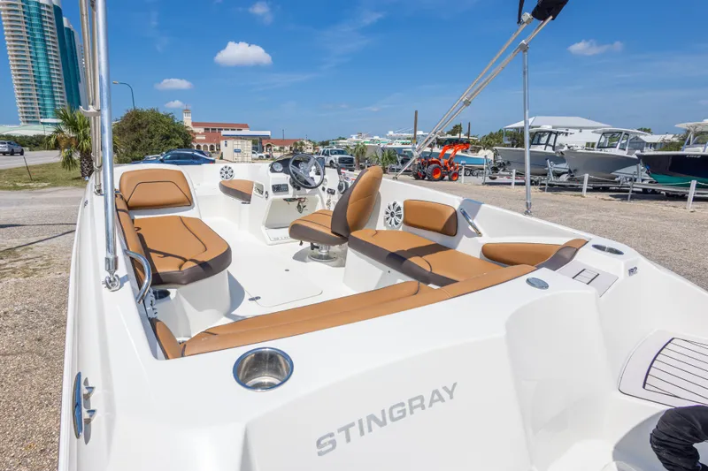 Slide: The Image of 2021 Stingray 182 SC boat with tan seating, docked under a clear blue sky. - 20