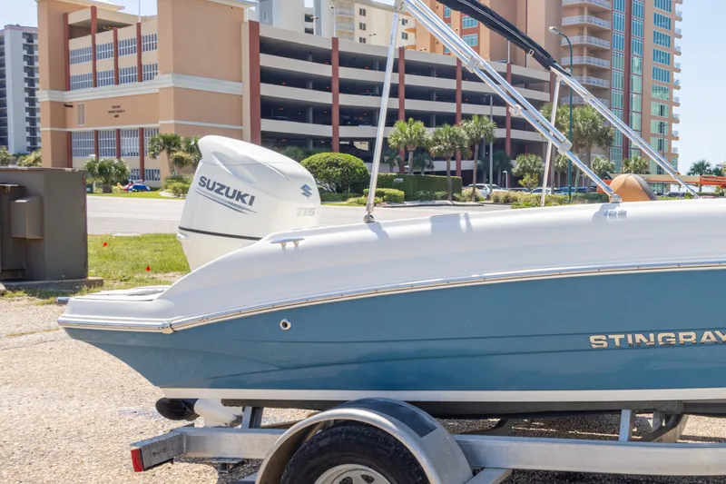 Slide: The Image of 2021 Stingray 182 SC boat with Suzuki engine on trailer, parked near buildings. - 10