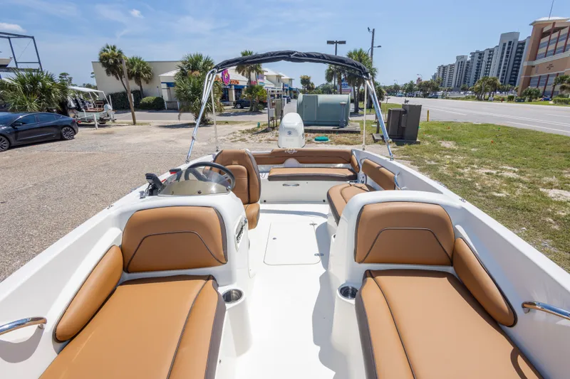 Slide: The Image of 2021 Stingray 182 SC boat with tan seating, parked near a road and buildings. - 29