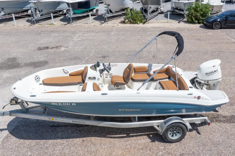Slide: The Image of 2021 Stingray 182 SC boat on trailer, featuring brown seating and Suzuki outboard motor. - 3