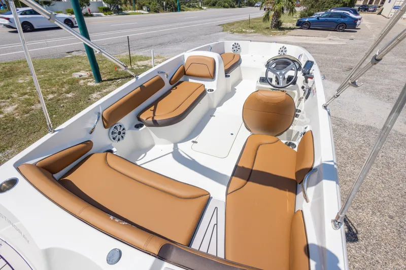 Slide: The Image of 2021 Stingray 182 SC boat interior with tan seating and steering wheel, parked near a road. - 21