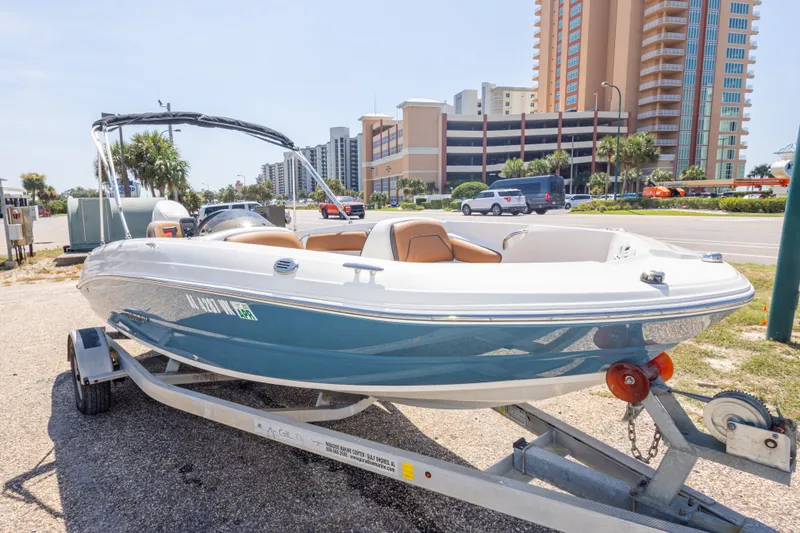 Slide: The Image of 2021 Stingray 182 SC boat on trailer, parked near modern buildings and palm trees. - 18
