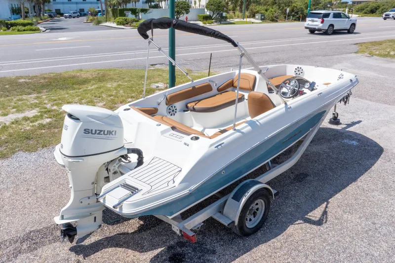 Slide: The Image of 2021 Stingray 182 SC boat with Suzuki outboard motor on a trailer, parked near a road. - 38