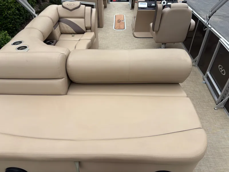 Slide: The Image of The image shows the interior of a 2019 Harris Sunliner 230 pontoon boat with beige upholstery. - 7