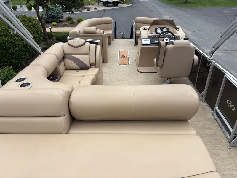 Slide: The Image of The image shows the interior of a 2019 Harris Sunliner 230 pontoon boat. It features beige upholstery and a modern helm. - 8