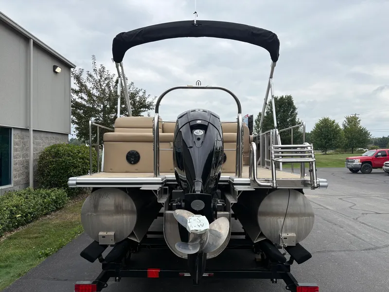 Slide: The Image of A 2019 Harris Sunliner 230 pontoon boat with a black Bimini top and outboard motor. - 5