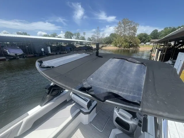 Slide: The Image of A 2022 Cobalt R8 Surf with a black sunshade, docked, surrounded by water and trees. - 11