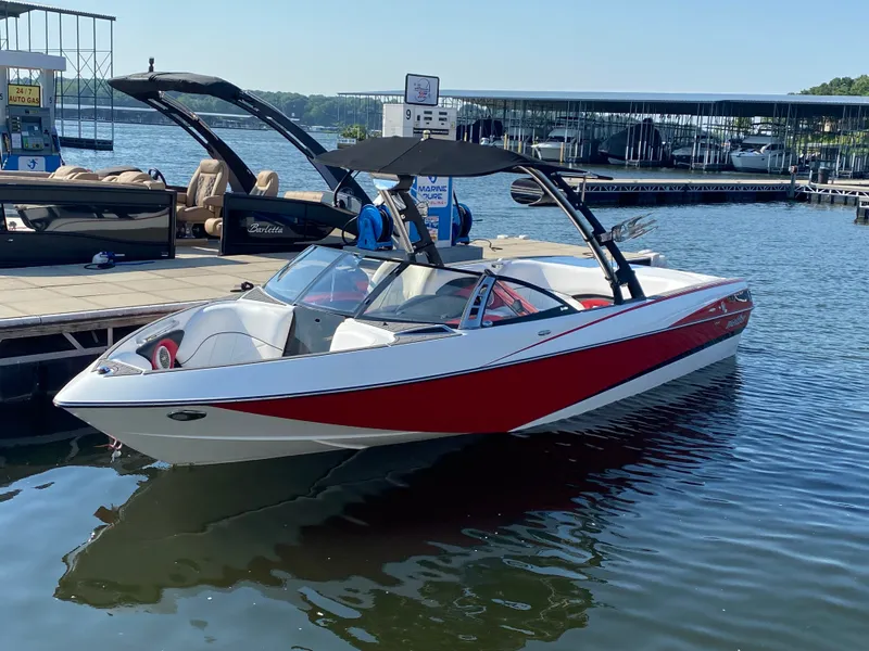 The Image of A red and white 2012 Malibu 247 LSV boat docked at a marina. - 1