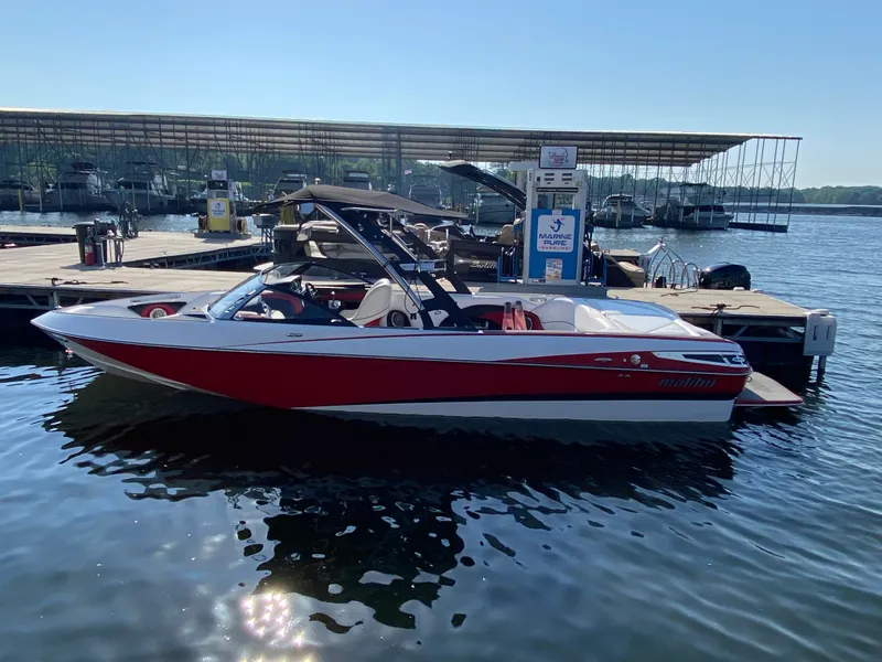 Slide: The Image of A red 2012 Malibu 247 LSV boat docked on a sunny day. - 2