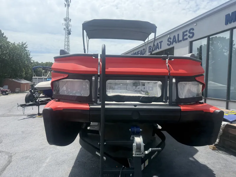 Slide: The Image of A red 2023 Sea-Doo Switch Cruise boat on a trailer outside a boat sales shop. - 2