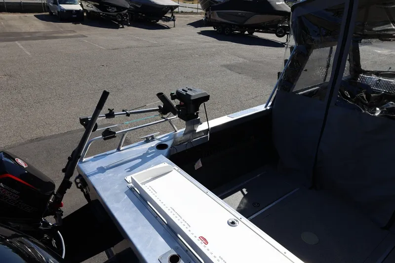 Slide: The Image of 2025 Thunder Jet 200 Luxor boat interior with fishing equipment and motor, parked outdoors. - 18