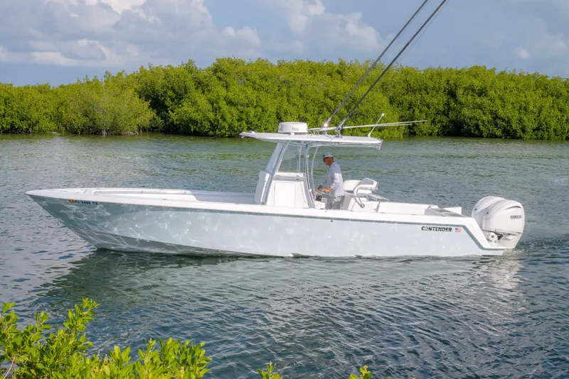 Slide: The Image of 2024 Contender 32 ST boat cruising on a calm waterway with lush greenery. - 2