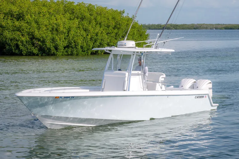 Slide: The Image of 2024 Contender 32 ST boat cruising on calm water near lush greenery. - 8