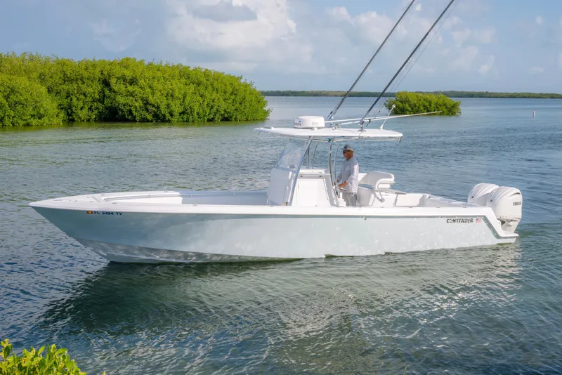 Slide: The Image of 2024 Contender 32 ST boat cruising on a calm waterway with lush greenery. - 6