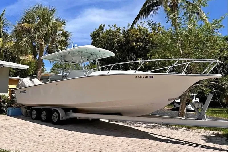 The Image of 1996 Jupiter 31 Center Console boat on trailer, surrounded by palm trees. - 1
