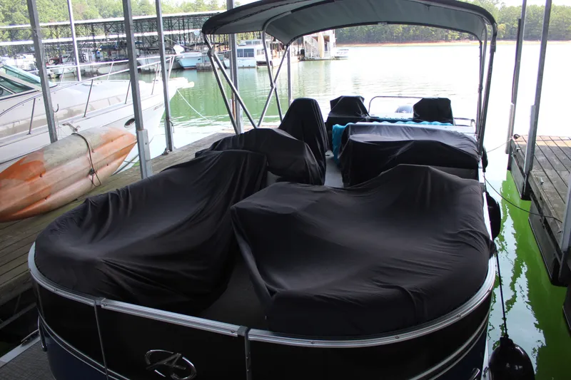 Slide: The Image of A 2024 Avalon LSZ RF 2585 pontoon boat is docked under a canopy, covered with black tarps. - 19