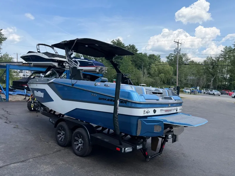 Slide: The Image of A blue 2025 Malibu Wakesetter 22 MXZ on a trailer. The sky is clear. - 18