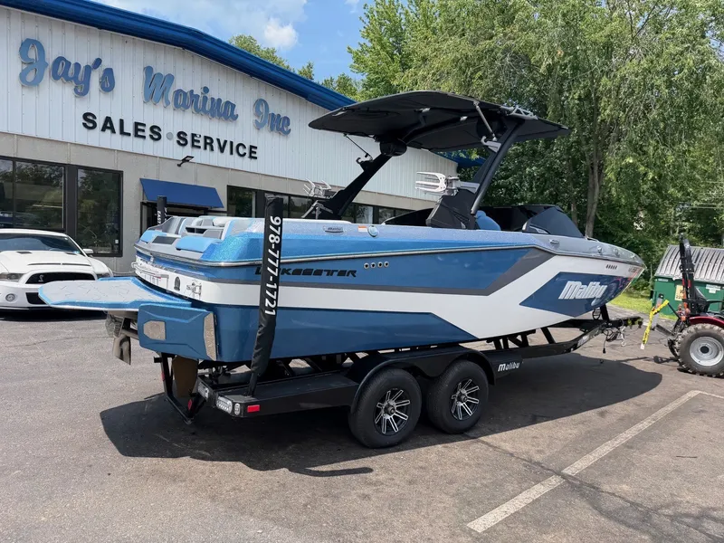 Slide: The Image of A blue 2025 Malibu Wakesetter 22 MXZ on a trailer in front of a building labeled "Jay's Marina Inc." - 7