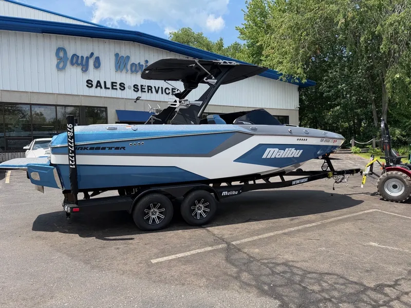 Slide: The Image of A blue 2025 Malibu Wakesetter 22 MXZ on a trailer in front of a building labeled "Jay's Marine." - 5