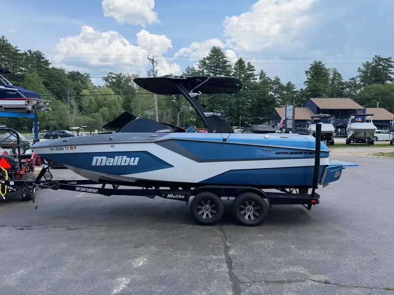 Slide: The Image of A blue 2025 Malibu Wakesetter 22 MXZ sits on a trailer in a parking lot. - 13